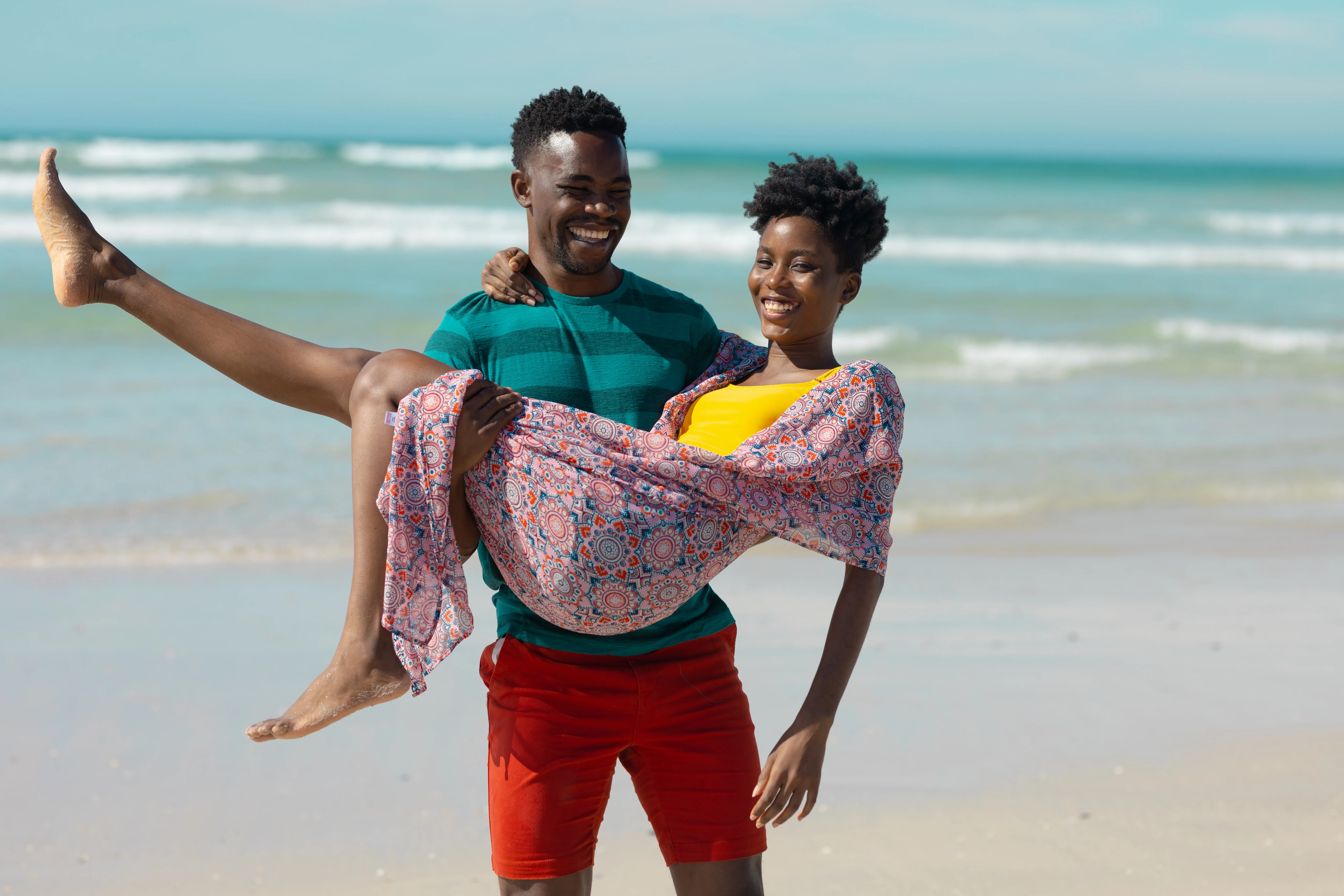 happy young man carrying young girl on a beach